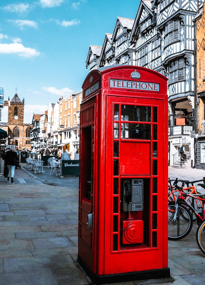 Vibrant red British telephone booth in historic Chester UK's street.