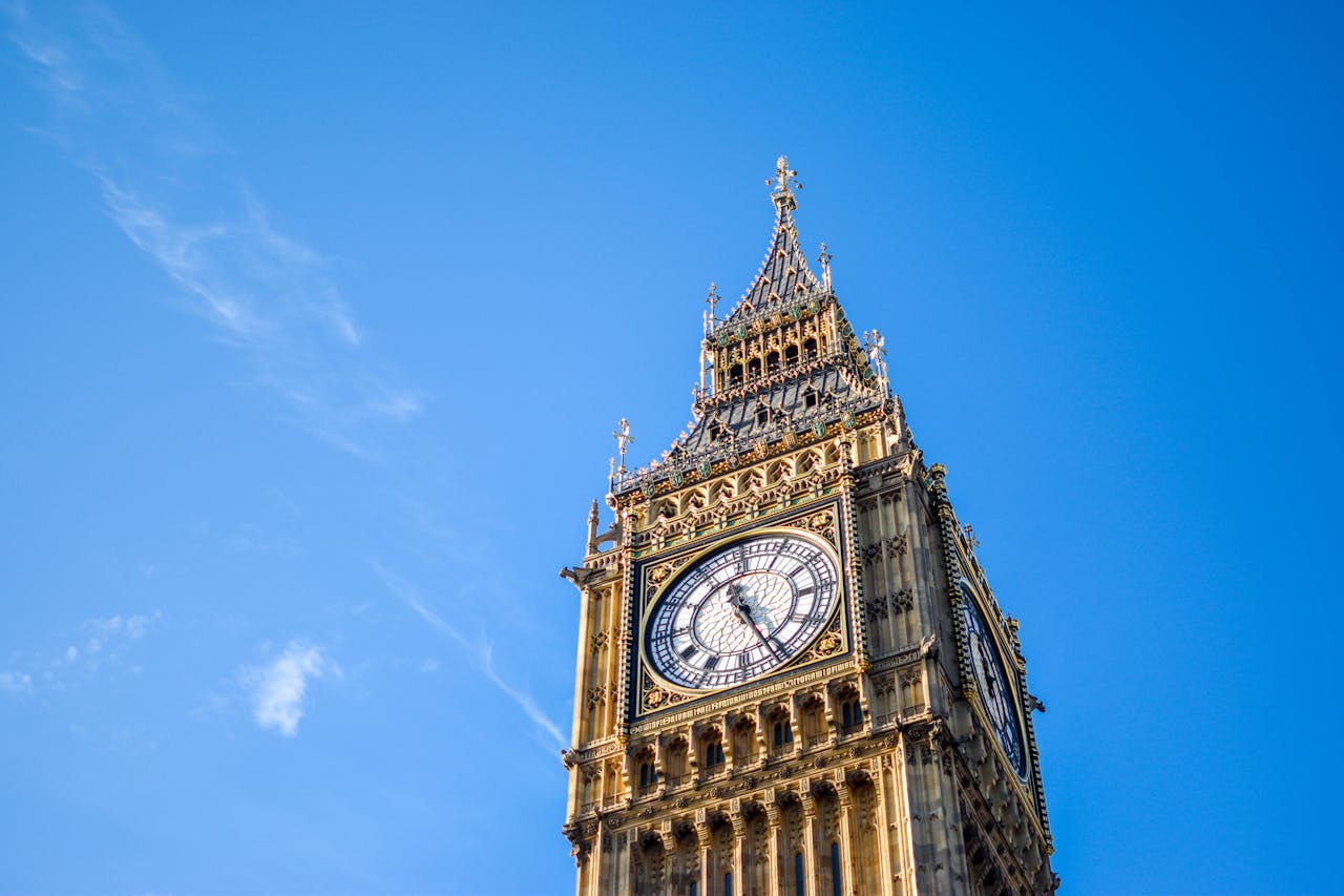 Stunning low angle view of Big Ben clock tower with a clear blue sky background, London landmark.